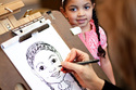 Young girl being drawn at birthday party