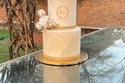 Buttercream wedding cake gold stenciling, white roses, cotton, berries